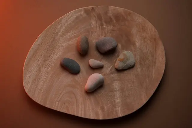 Balanced, smooth river stones on a wooden tray, symbolizing safety and IFS trauma therapy in San Francisco.